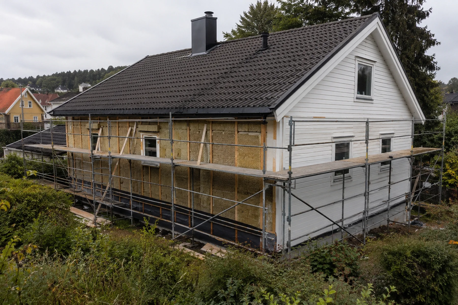 Eldre bolig under utvendig etterisolering med stillas, åpen fasade, isolasjon og kledning
