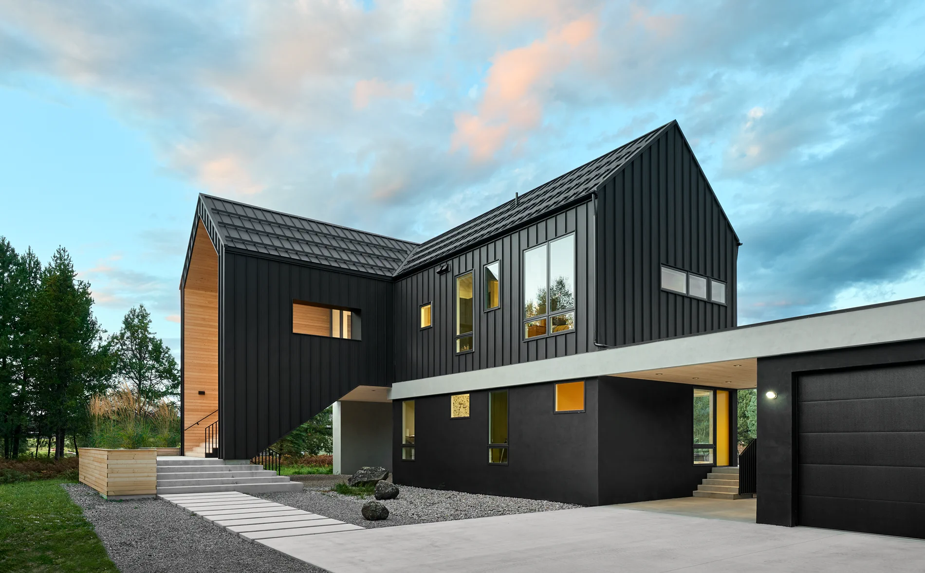 Moderne bolig med mørk stående kledning, treinnslag, store vinduer og tydelig fasadeuttrykk