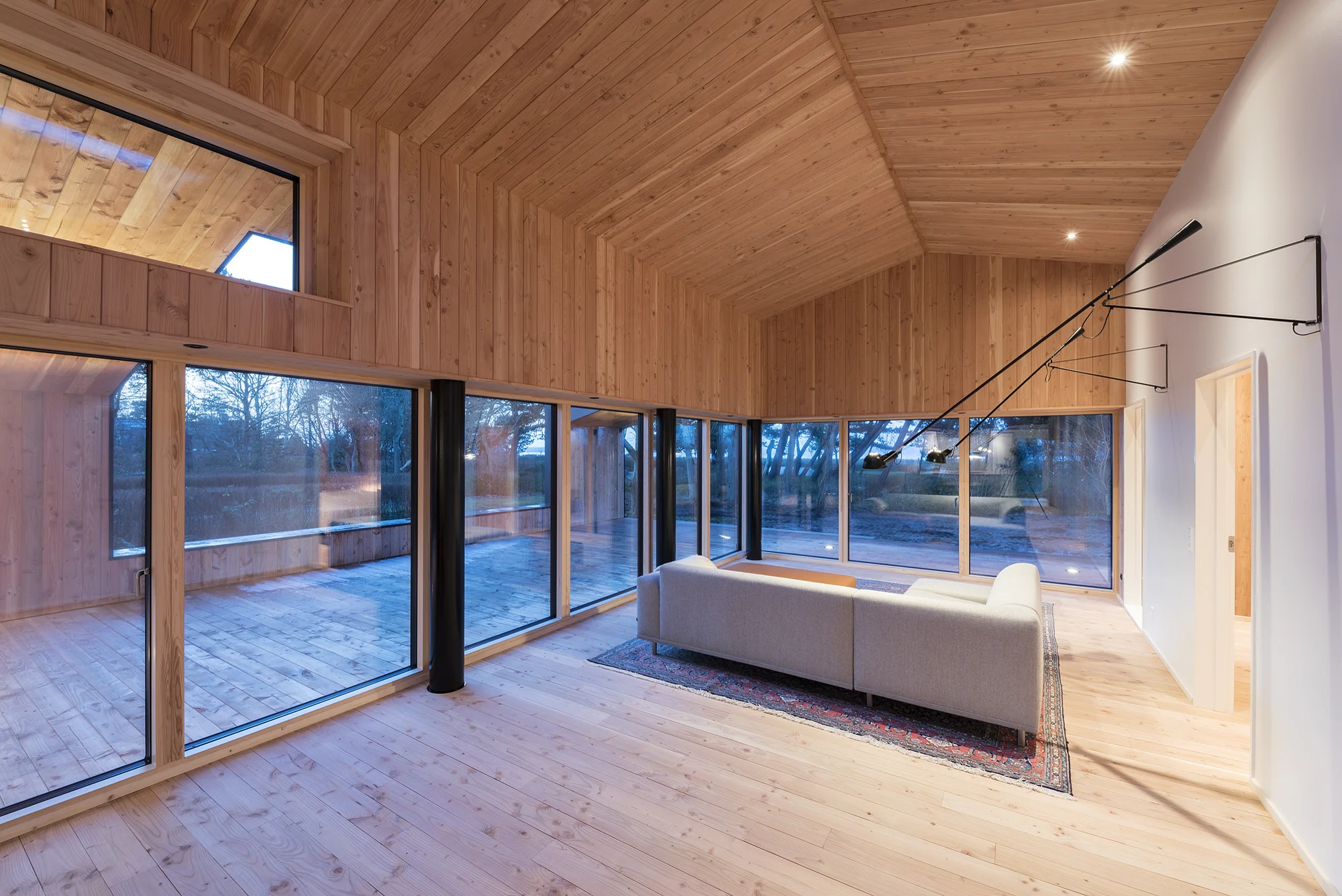 Oppholdsrom med trehimling, tregulv og store vinduer