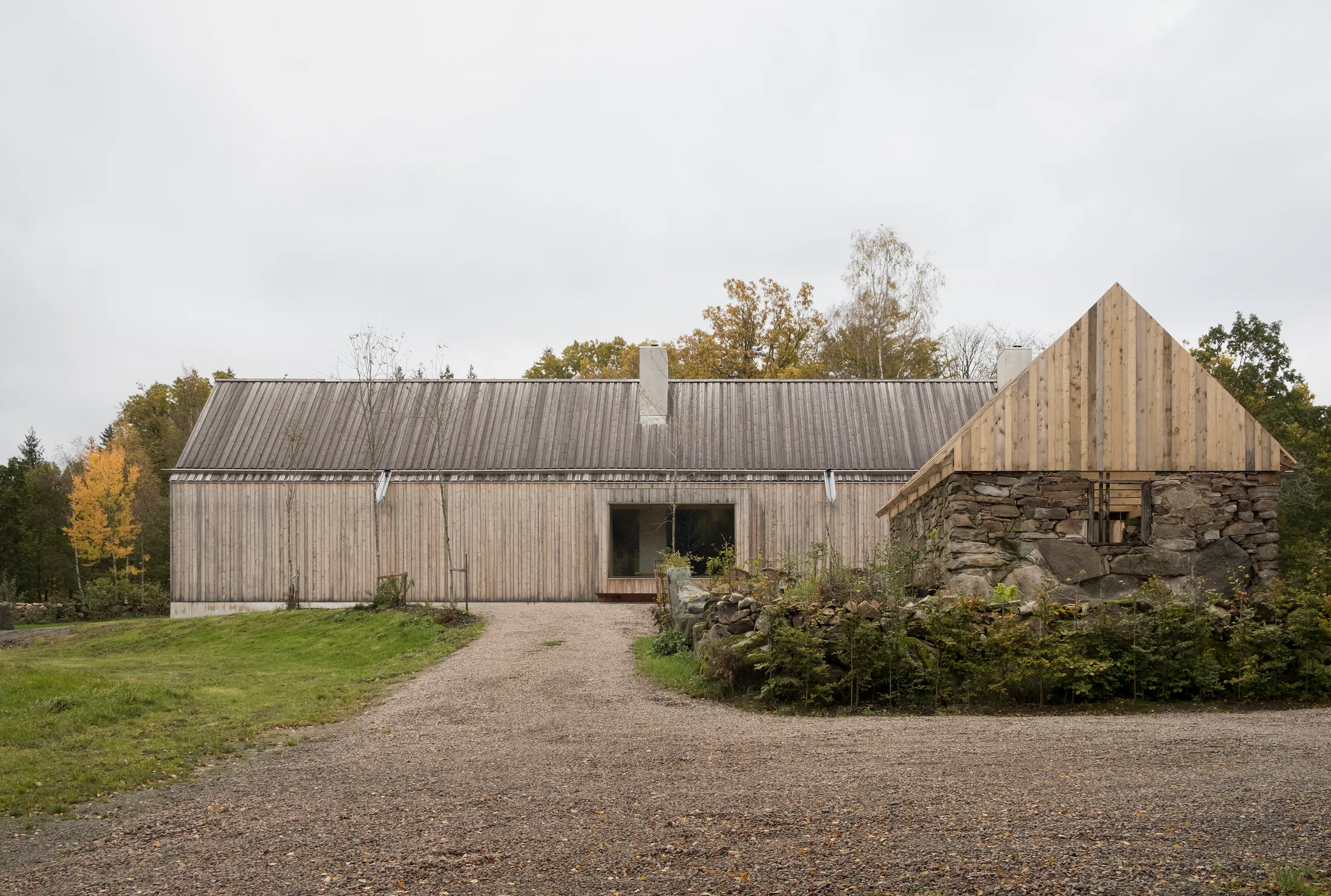 Trekledd bolig med grusvei og steinmur