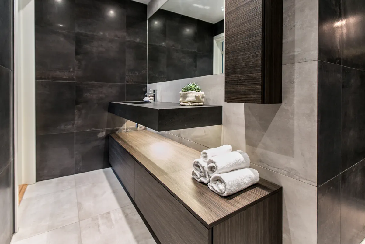 Finished Asker bathroom with dark tile, floating vanity, mirror, and folded towels