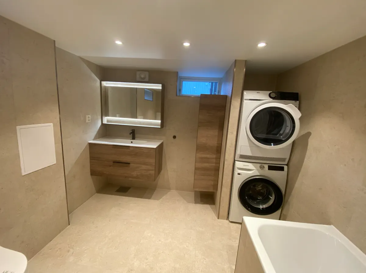 Asker basement bathroom and laundry area with stone tile, mirror, and stacked appliances