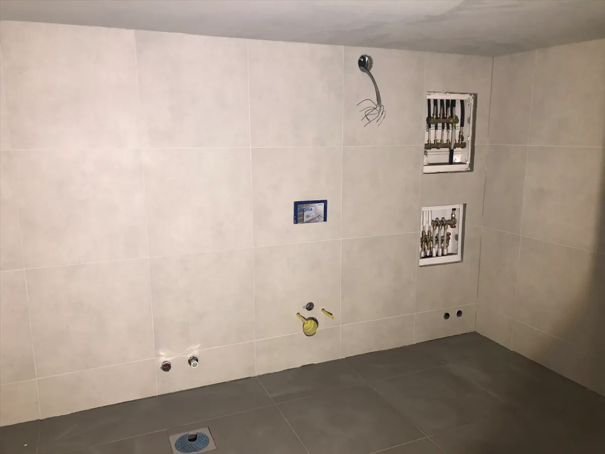 Hosle basement floor renovation in progress with tiled walls and open plumbing points