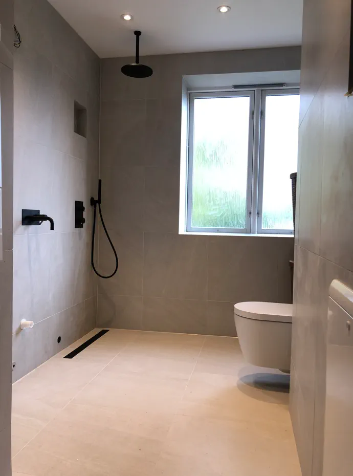 Skøyen bathroom renovation in progress with grey tile, shower fittings, and bright window
